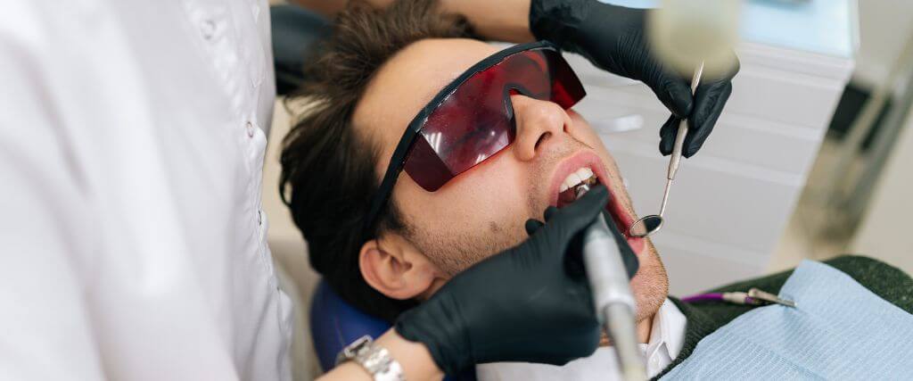Man at dentist using laser for procedure.